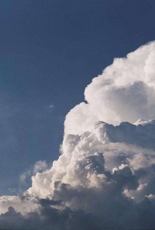 A large cumulus cloud fills the right side of the frame against a blue sky.