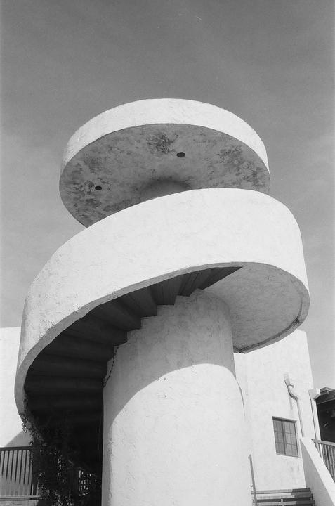 A spiral staircase with a round platform above it is shown from a low angle.