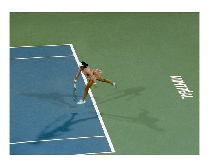 A woman in a pink dress plays tennis on a blue and green court with "MONTREAL" written on it.