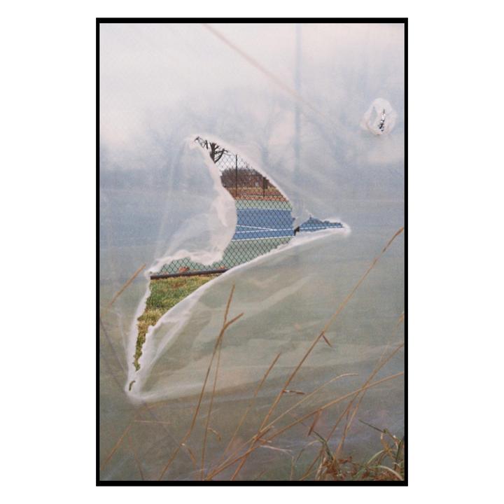 A tennis court is visible through a tear in a white tarp.