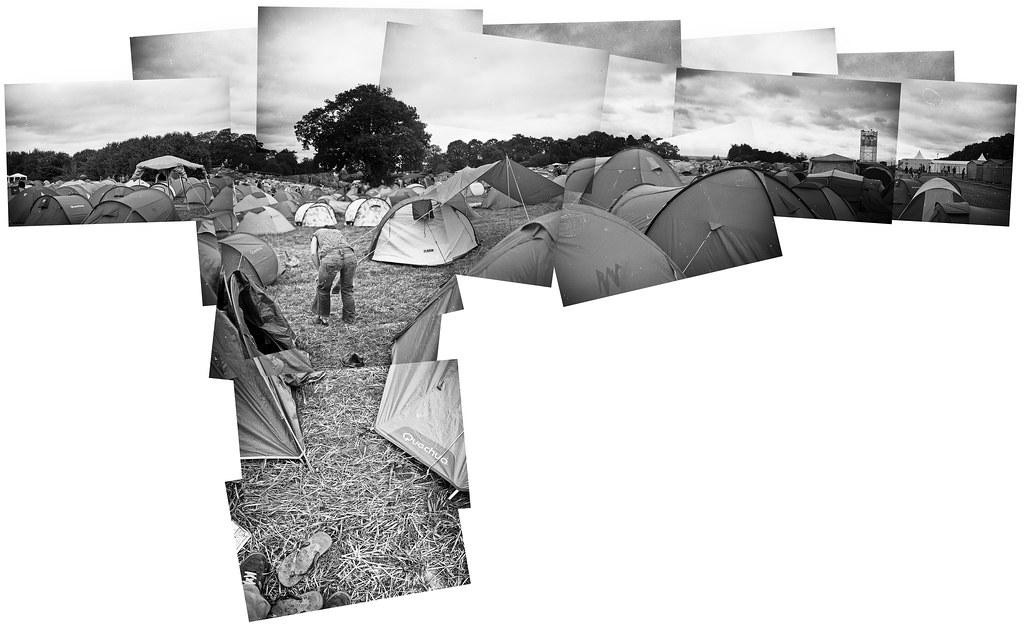 A man bends over in a field filled with tents under a cloudy sky.