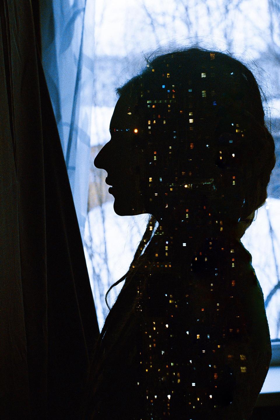 A woman's silhouette is visible in a double exposure with city lights.