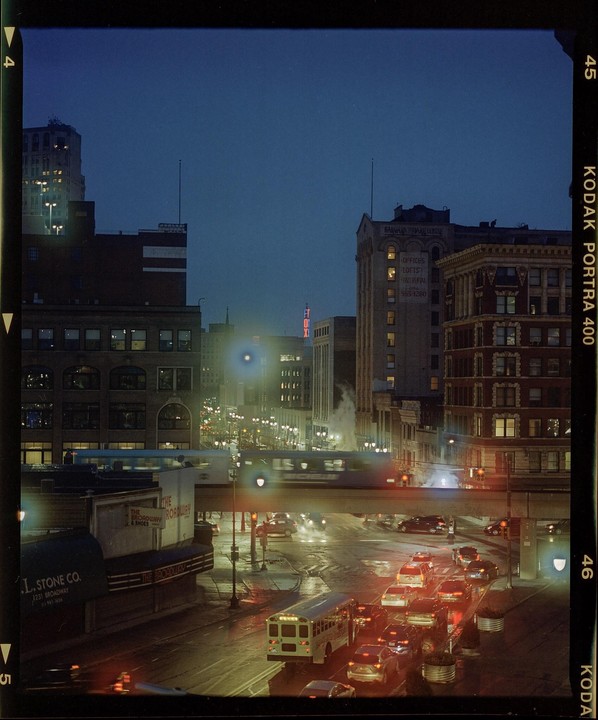 A street in Detroit is filled with traffic and illuminated by city lights at night.