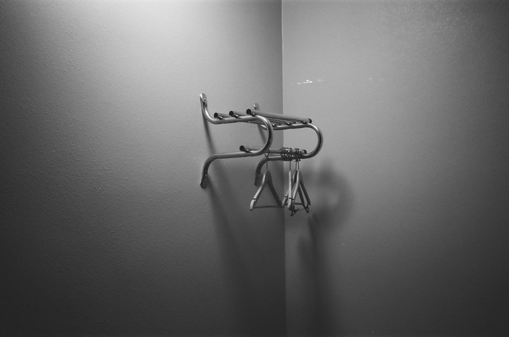 A metal luggage rack with several hangers hangs on a wall in a corner.