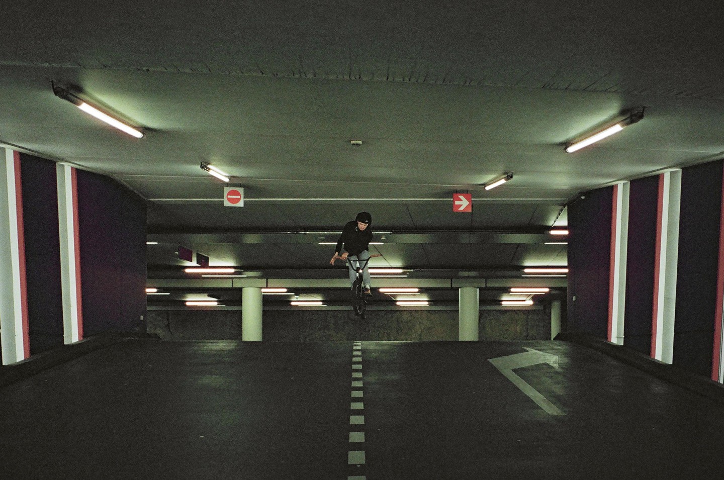 A boy on a bicycle is airborne in a parking garage.