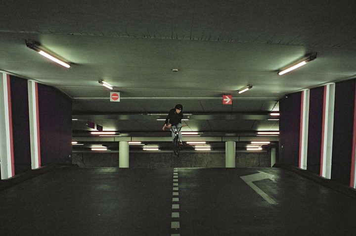 A boy on a bicycle is airborne in a parking garage.