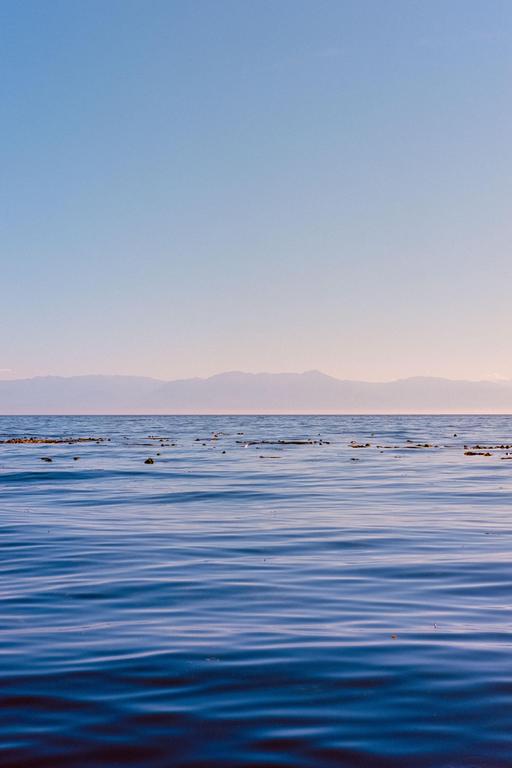 The ocean with mountains in the distance is visible under a clear sky.