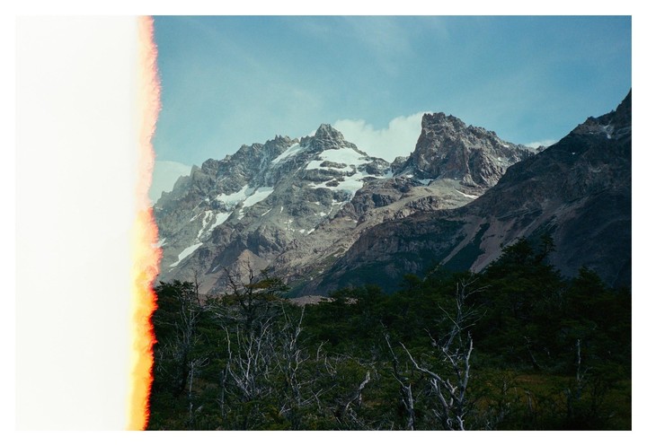 A light leak is visible on the left side of a landscape photo of mountains with snow-capped peaks and a forest.
