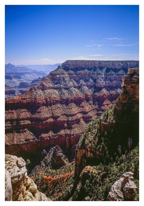 A vast canyon landscape with layered rock formations and a clear blue sky is visible.