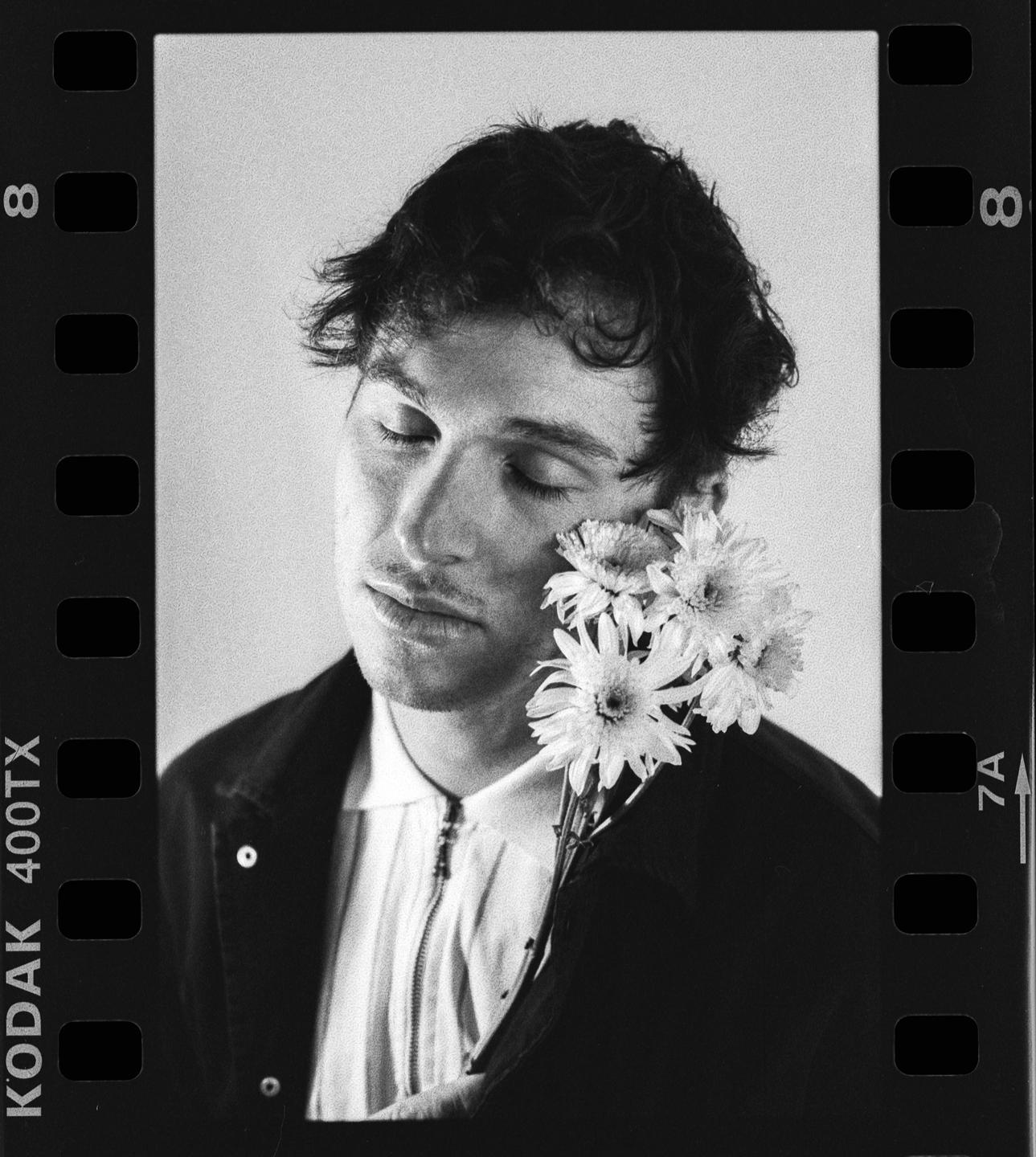 A man with closed eyes holds a bouquet of flowers to his face.