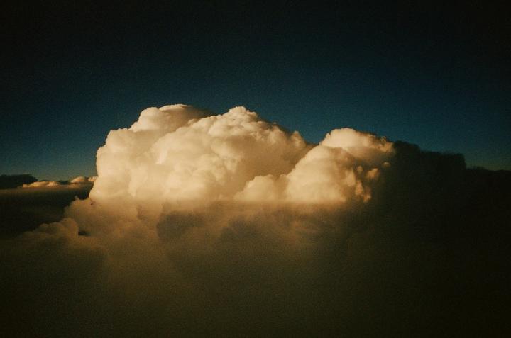 A large, brightly lit cloud formation is visible against a dark blue sky.