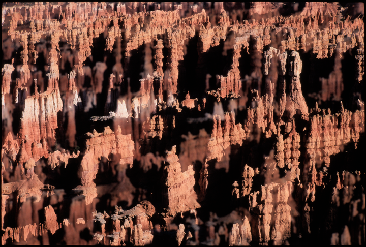 A double exposure shows a canyon wall with many hoodoos and deep shadows.