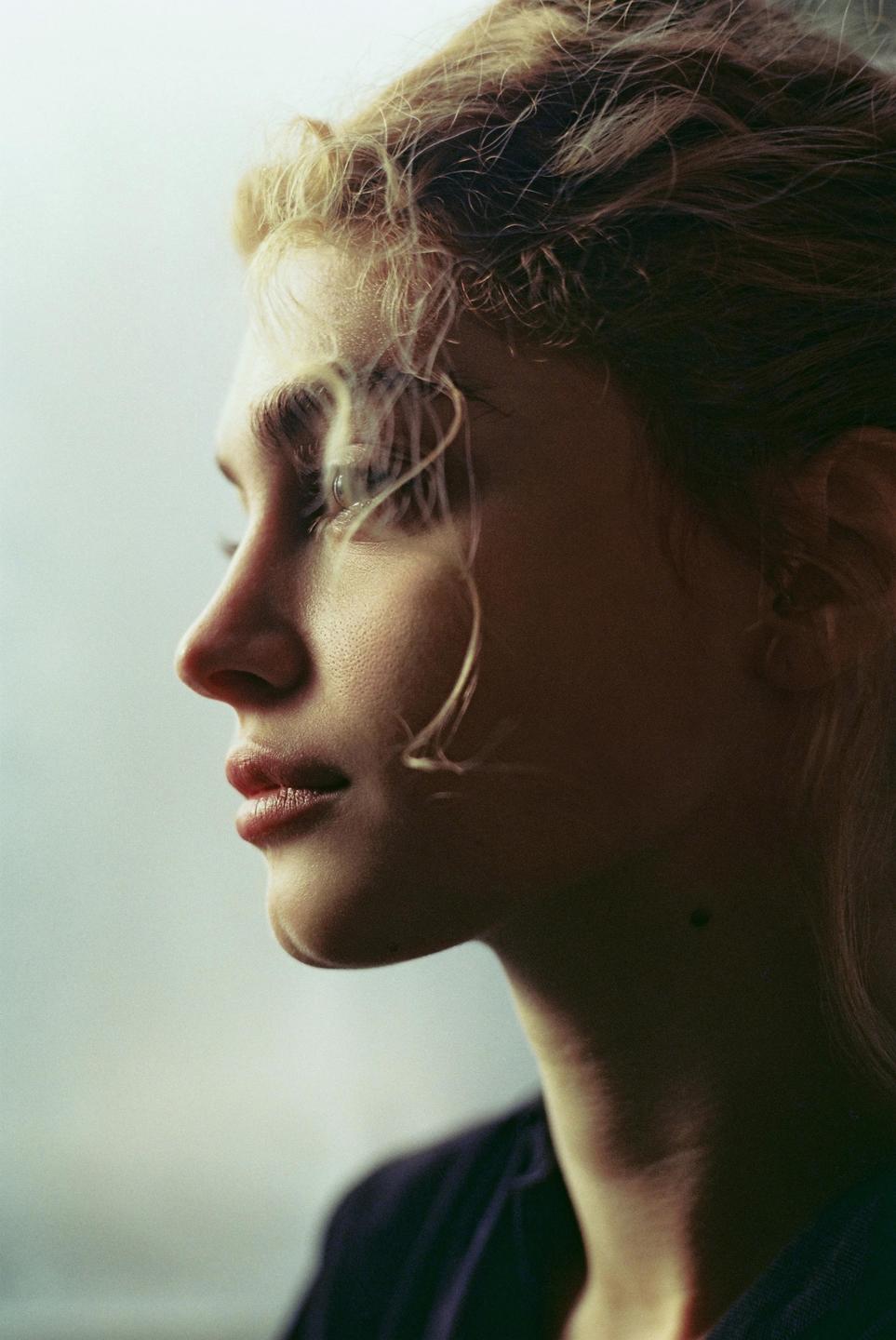 A woman with curly hair looks to the right of the frame.