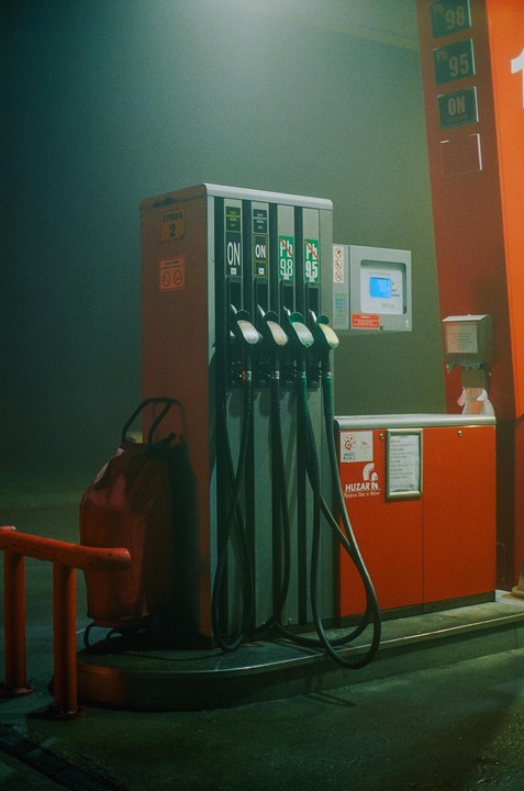 A gas pump with multiple nozzles stands in a hazy, dimly lit environment.