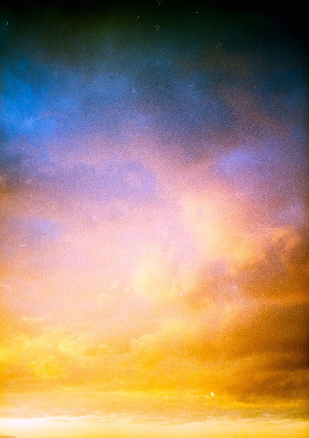 The sky is filled with clouds illuminated by the setting sun, creating a gradient of blue, purple, pink, and orange hues.