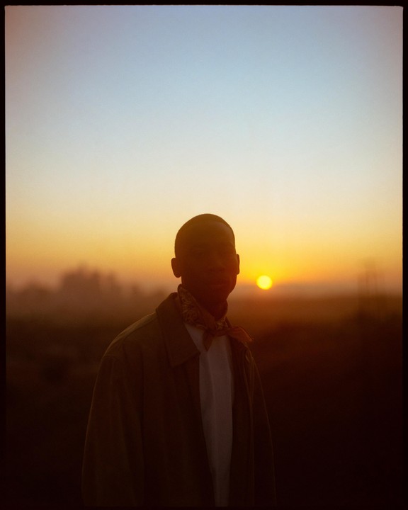 A man stands silhouetted against a vibrant sunset.