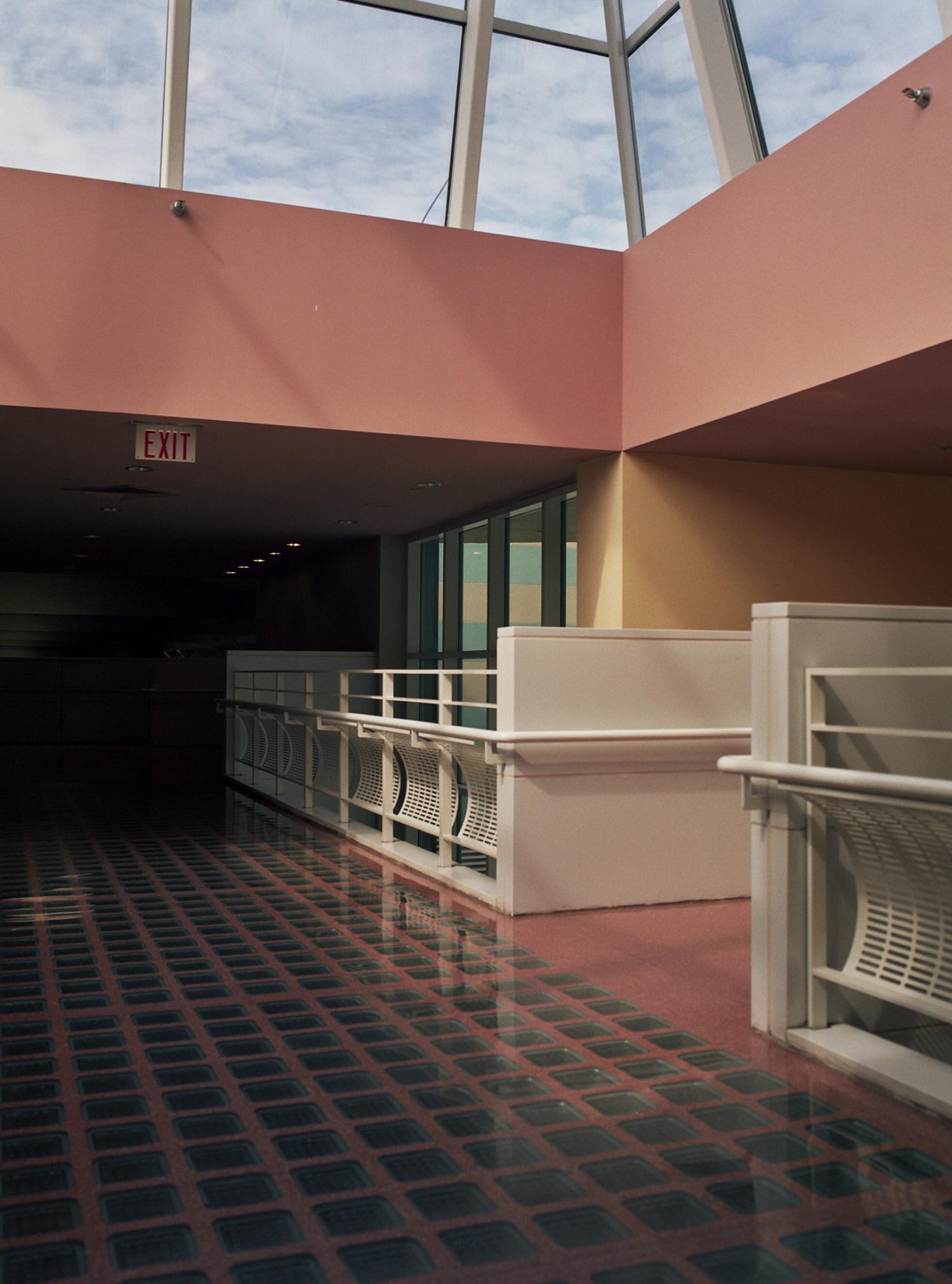 A pink and yellow interior with a glass block floor and an exit sign.