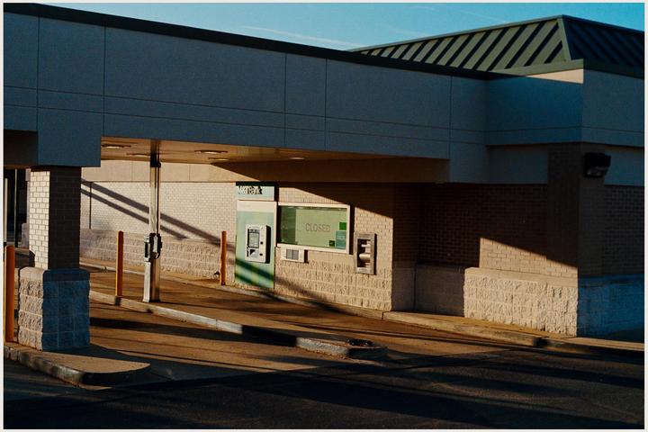 A closed bank drive-through is illuminated by the golden hour sun.