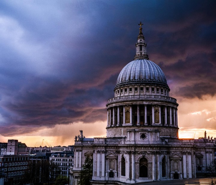 St Paul's Cathedral stands under a dramatic, cloudy sky with a colorful sunset.
