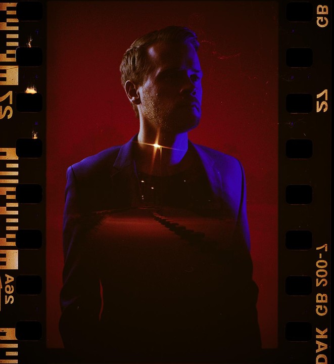 A man in a suit is double exposed with a night road scene.