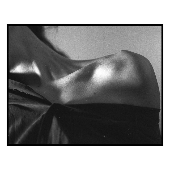A woman's shoulder and collarbone are highlighted by light.