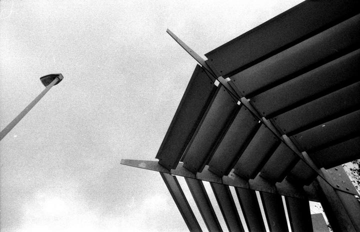 A street light and a slatted structure are visible against a bright sky.