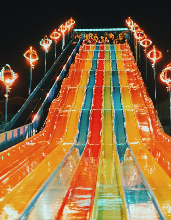 A colorful amusement park slide is illuminated at night.