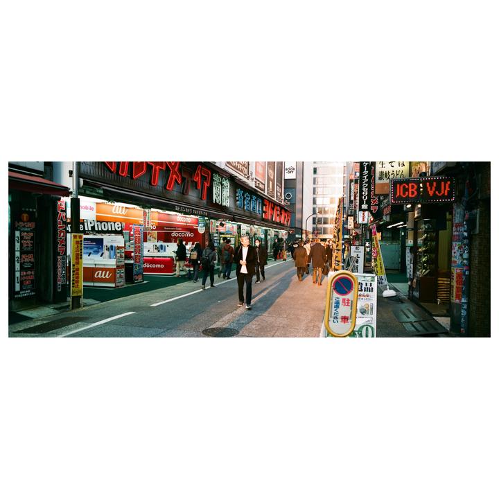 A street in Japan is filled with pedestrians and neon signs.