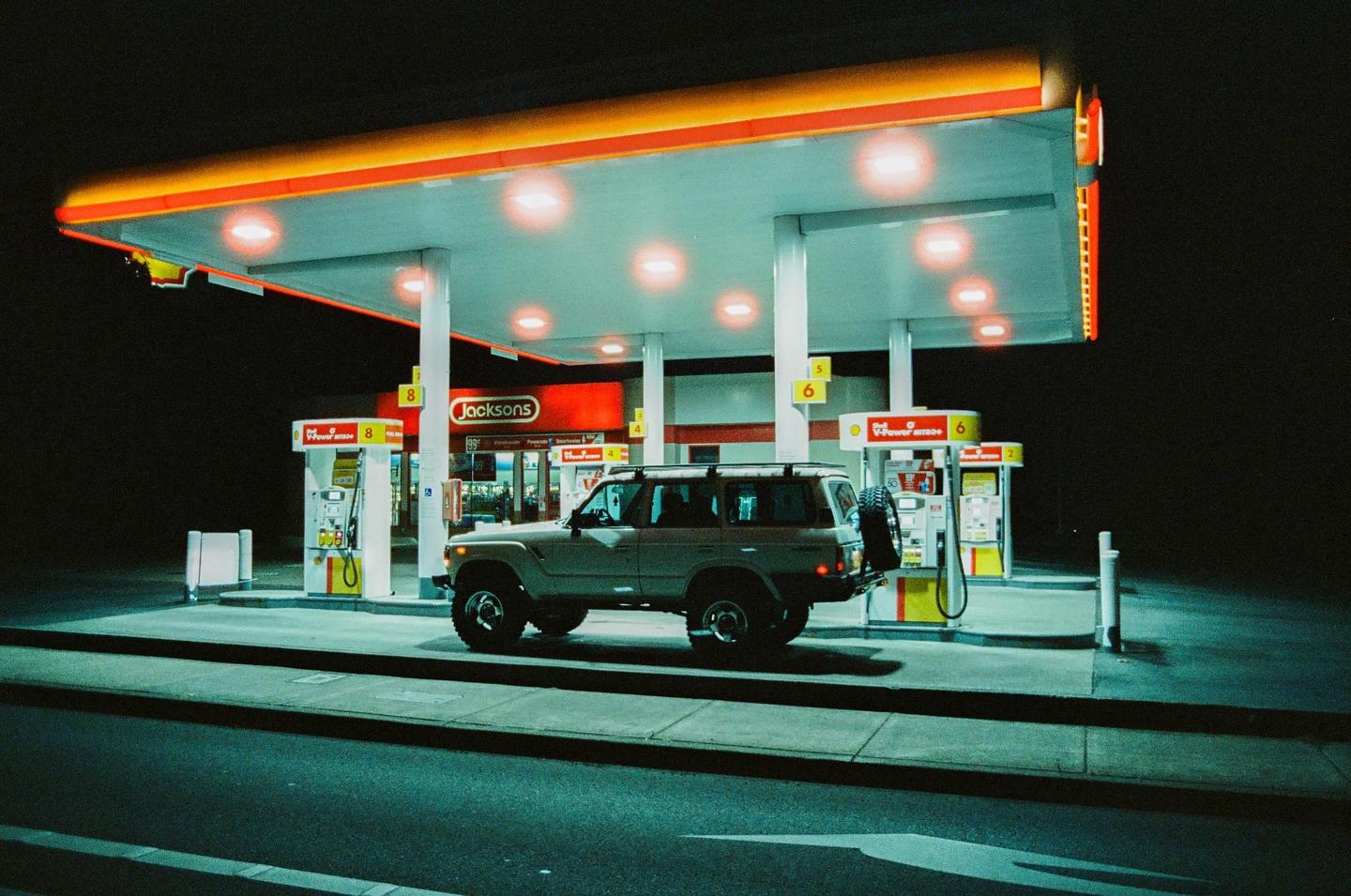 A sport utility vehicle is parked at a gas station at night.