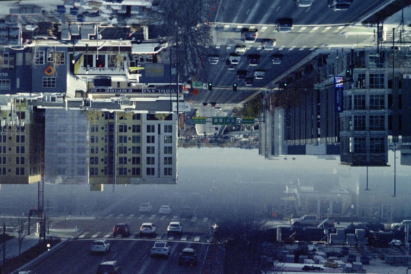 A double exposure shows a street with cars and buildings, with one exposure inverted.